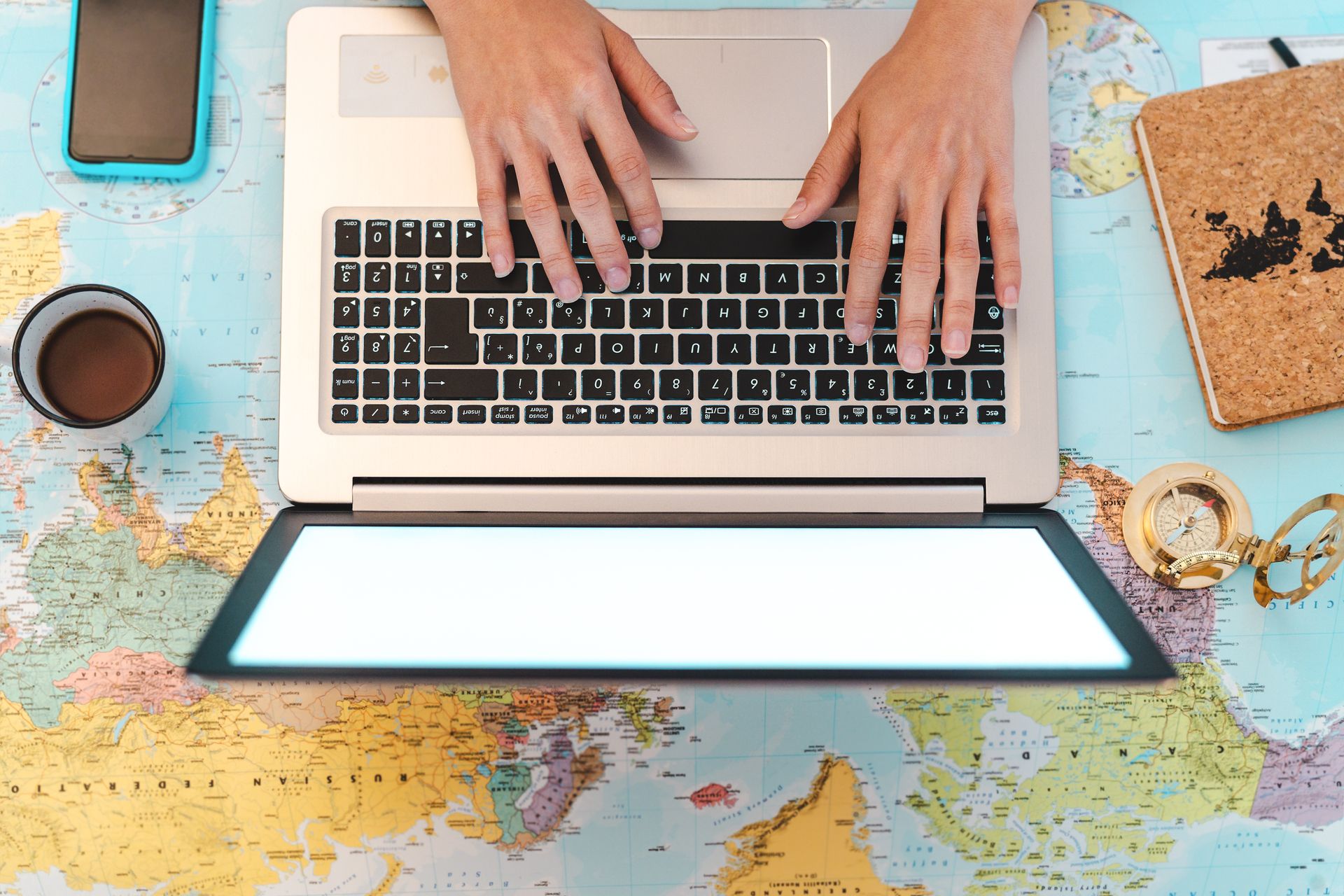 Planning a business trip on a laptop over a world map