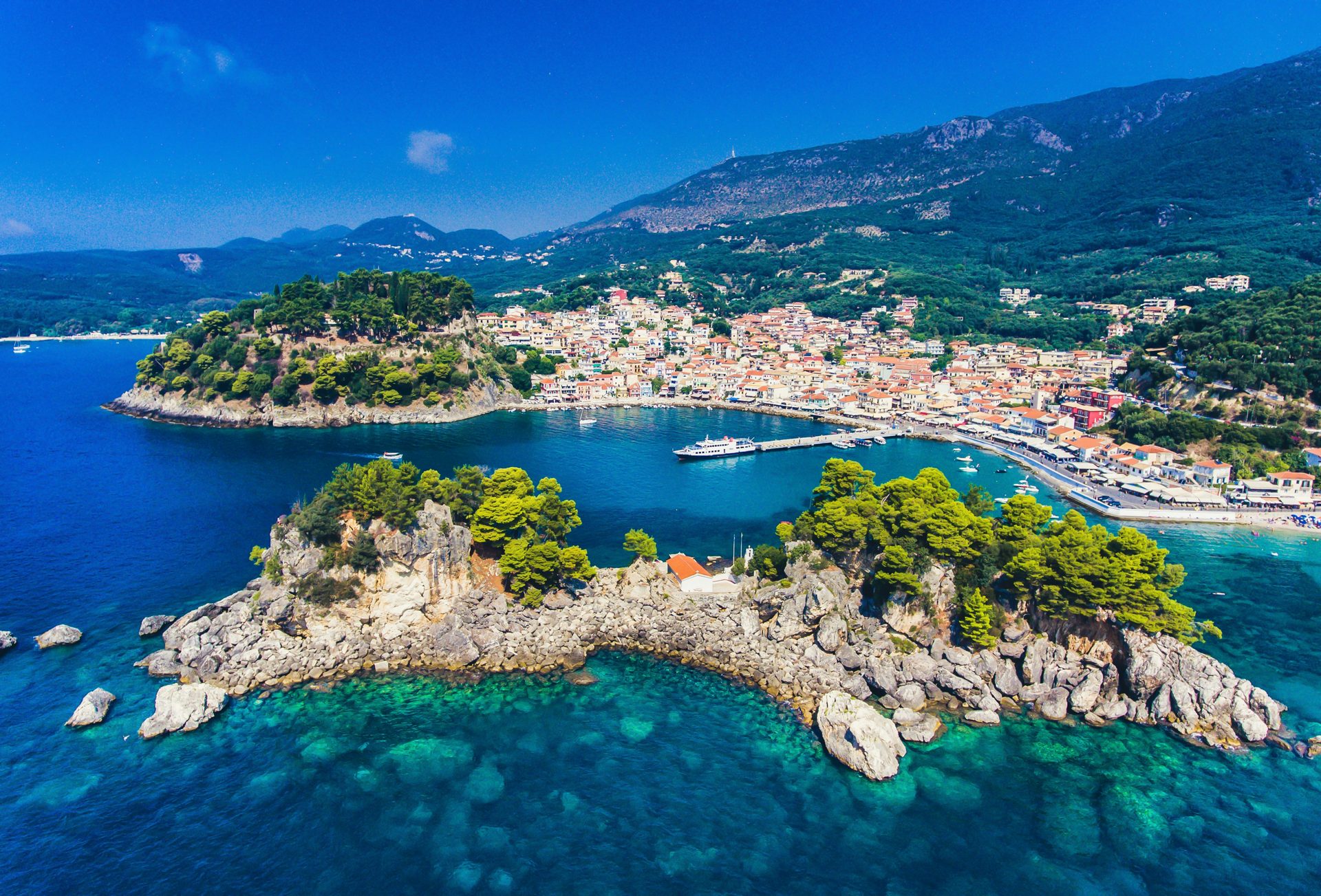 A green island and harbor town in clear blue Mediterranean water