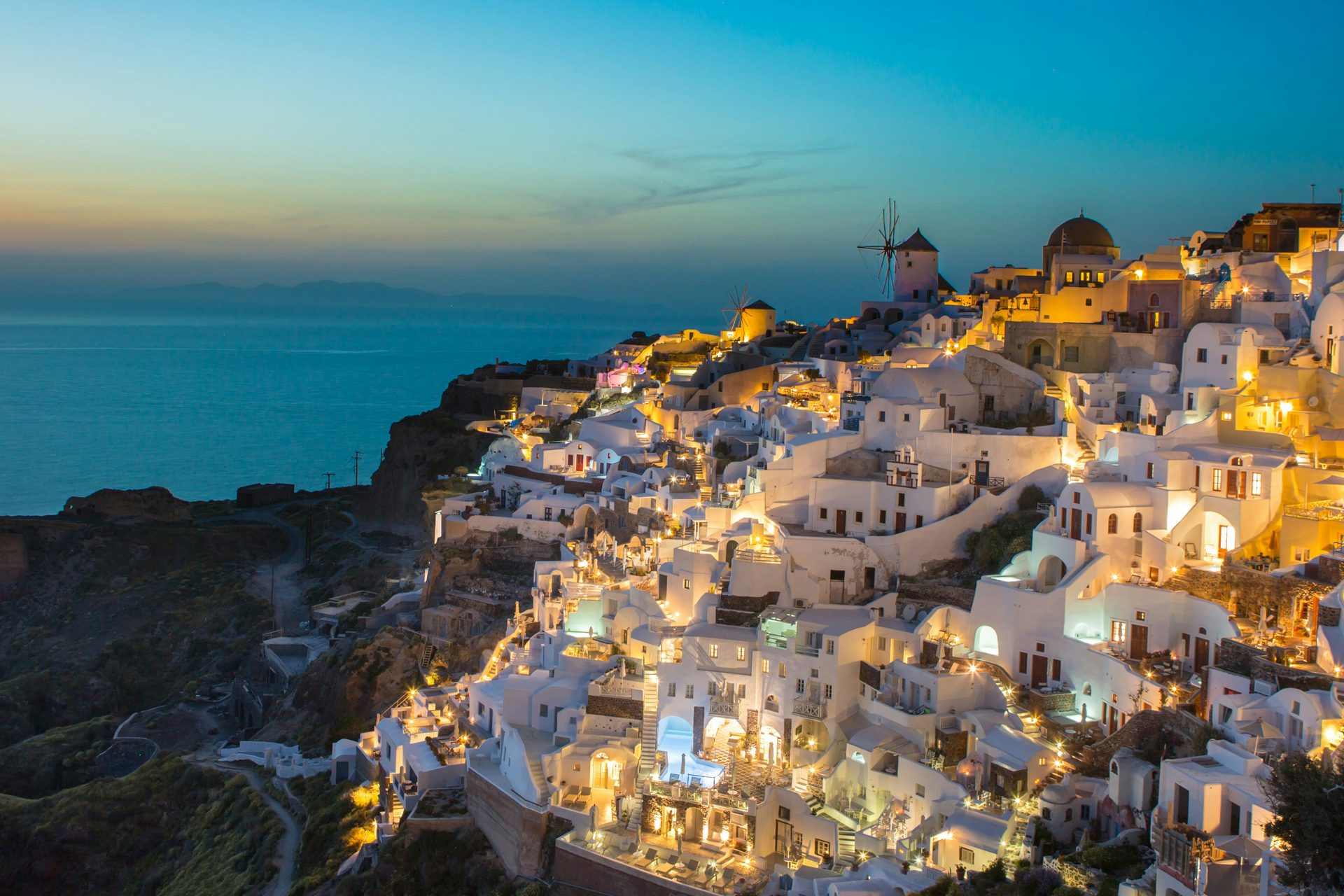The village of Oia on Santorini lit up along the cliffs at dusk