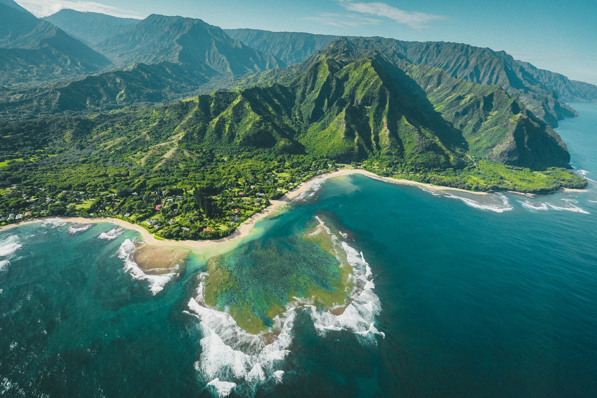 Aerial view of green Na Pali cliffs above a turquoise bay