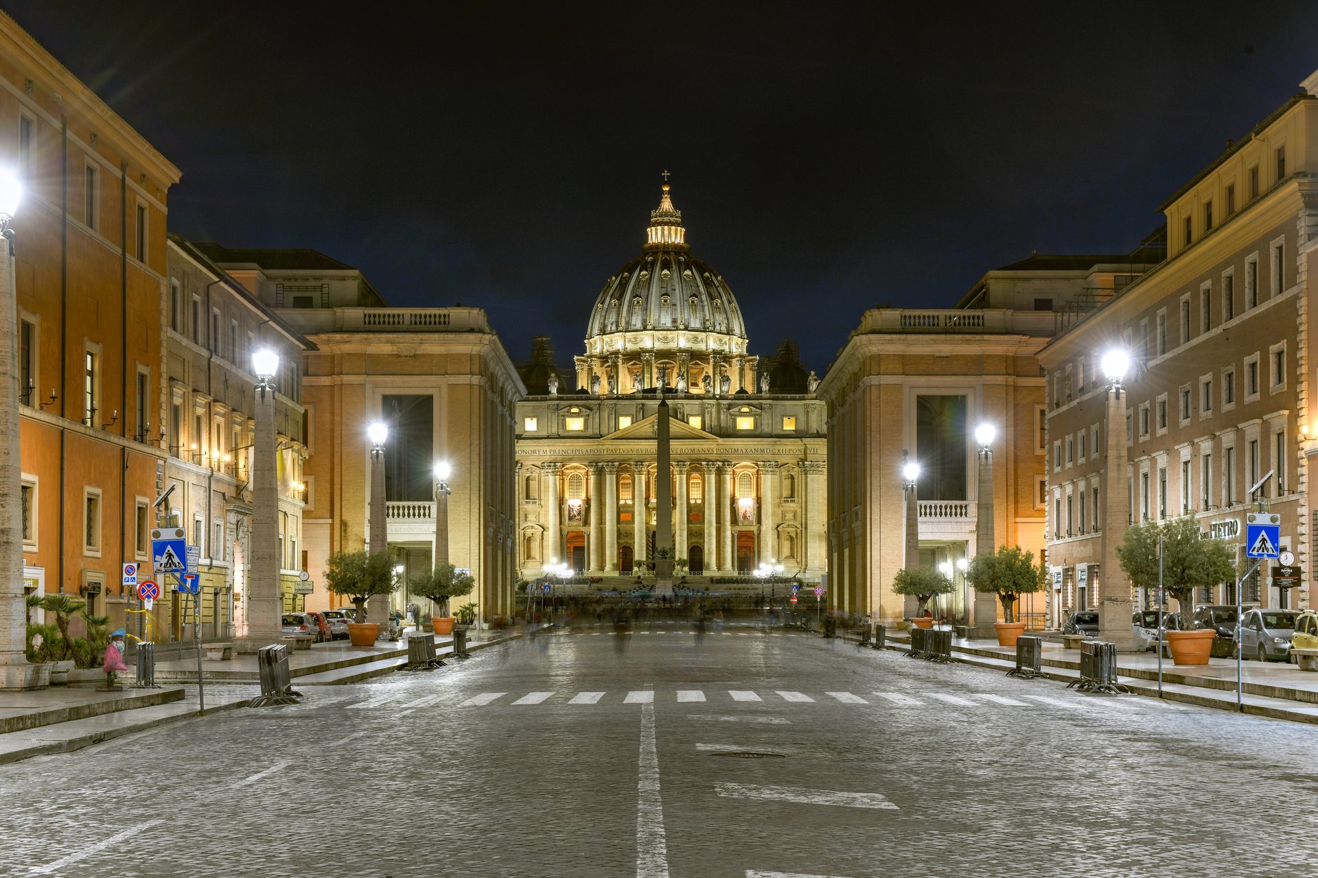St. Peter's Basilica in Vatican City lit up at night at the end of a long avenue
